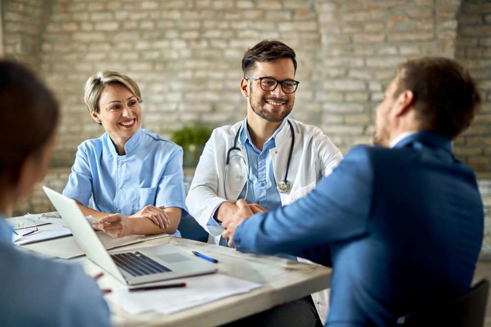 group-healthcare-workers-greeting-financial-advisor-during-meeting-office